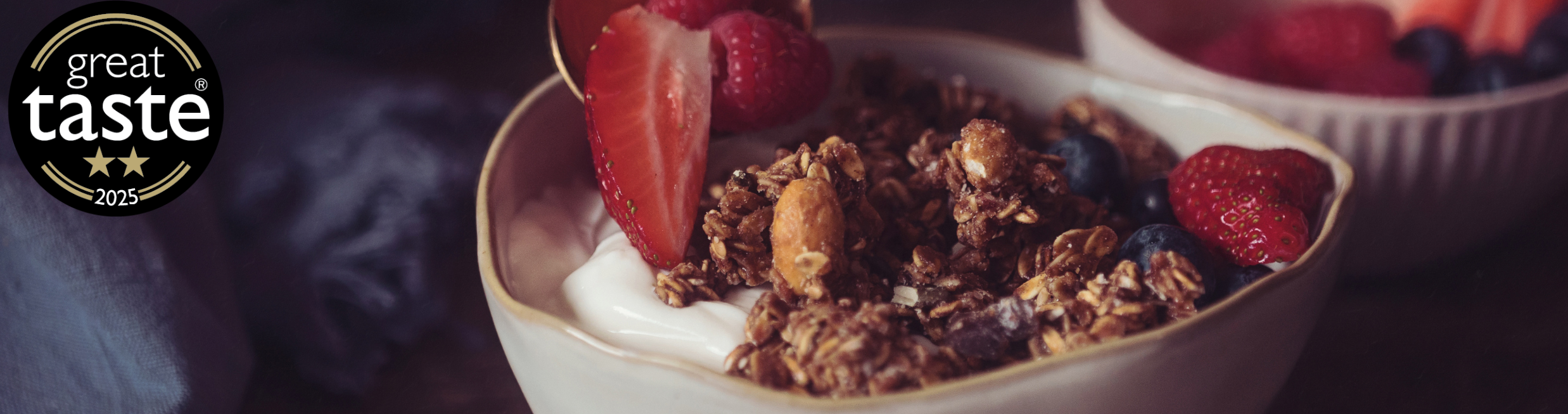 Bowl of granola with fruit and a two start great taste award sticker